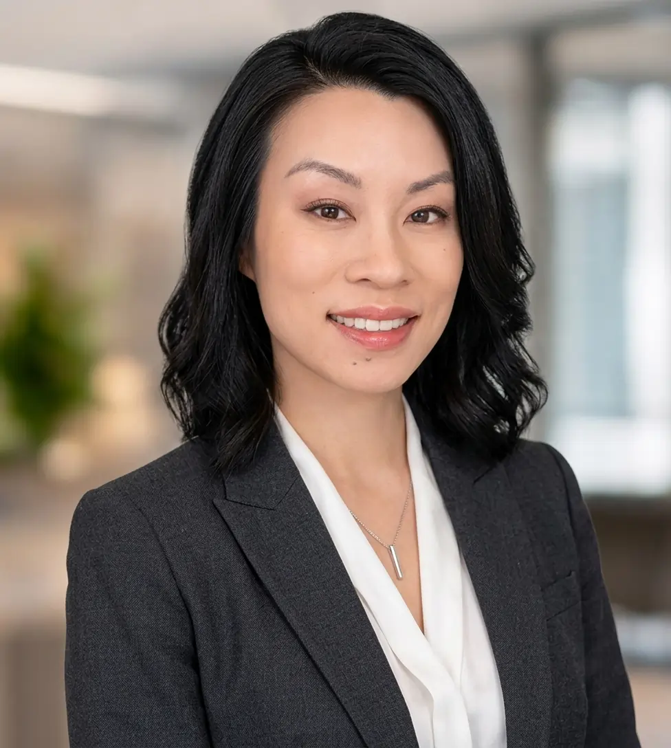 Sarah Chen in dark blazer smiling in a modern office environment with soft background lighting